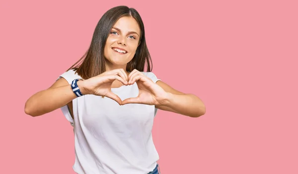 年轻的高加索女人穿着随意的白色T恤 带着爱的笑容用手做心形符号 浪漫的概念 — 图库照片