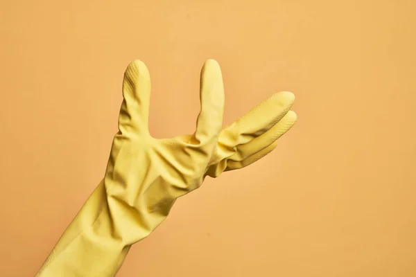 白人年轻人的手 戴着清洁手套 穿过孤立的黄色背景 拿起看不见的东西 手拿着显示空间的东西 — 图库照片