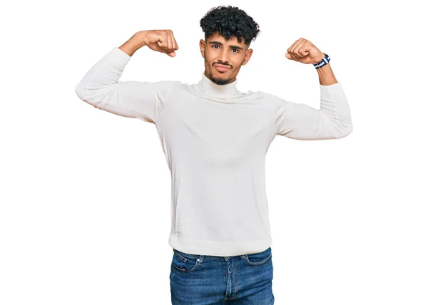 年轻的阿拉伯男子穿着休闲地冬季毛衣 露出胳膊肌肉 笑着感到自豪 健身概念 — 图库照片