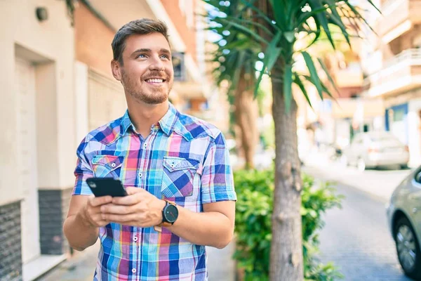 Mladý Kavkazský Muž Usměvavý Šťastný Pomocí Smartphonu Městě — Stock fotografie