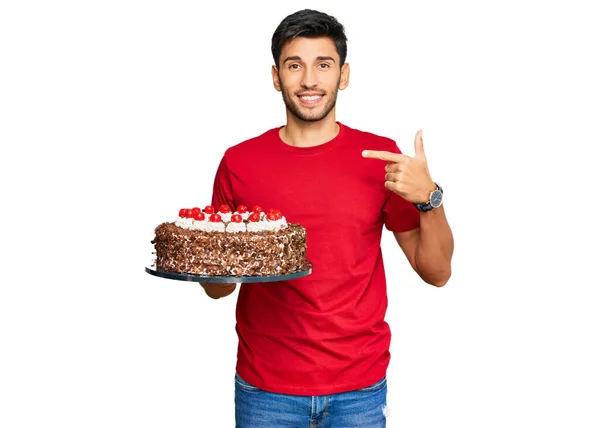 年轻英俊的男人用蛋糕指着一个人庆祝生日 面带微笑 快乐而自豪 — 图库照片