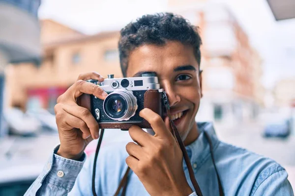若いですラテン観光の男笑顔幸せな使用してヴィンテージカメラ歩行で街 — ストック写真