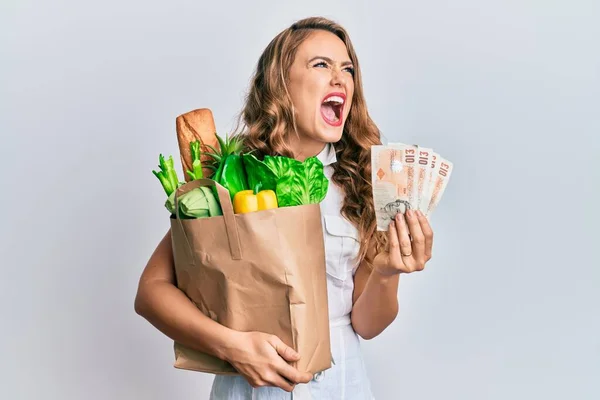 Young Blonde Girl Holding Paper Bag Groceries Pounds Angry Mad — Stock Photo, Image