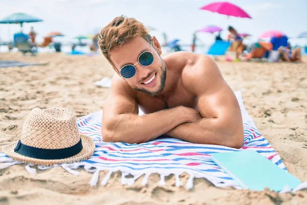 タオルの上に横たわる晴れた日の日光浴でビーチでハンサムなフィットネス白人男性 — ストック写真
