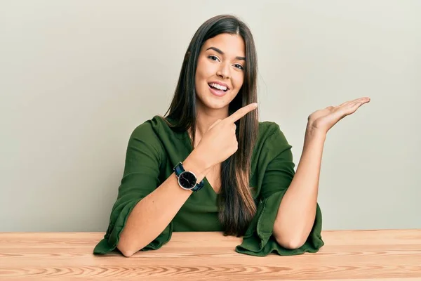 Joven Morena Vestida Con Ropa Casual Sentada Mesa Sorprendida Sonriendo — Foto de Stock