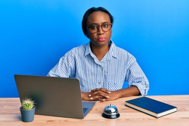 Genç Afrikalı bir kadın otel resepsiyonunda dizüstü bilgisayar kullanarak çalışıyor. Depresyonda ve endişe içinde, sinirli ve korkmuş bir şekilde ağlıyor. hüzünlü ifade. 