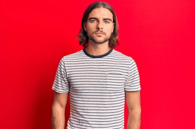 Yüzünde ciddi bir ifade olan sıradan kıyafetler giyen genç yakışıklı bir adam. Basit ve doğal bir şekilde kameraya bakıyorsun.. 