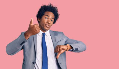 Afro saçlı, iş ceketi giyen yakışıklı Afro-Amerikalı bir adam. Baş parmak kaldırıyor, anlaşmazlık ve anlaşma ifadesi takınıyor. çılgın çatışma 