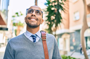 Genç Afrikalı Amerikalı iş adamı gülümseyerek şehirde mutlu bir şekilde yürüyor..