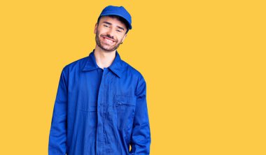 Genç İspanyol ressam üniforması giyiyor. Pozitif ve mutlu görünüyor. Duruyor ve gülümsüyor. 