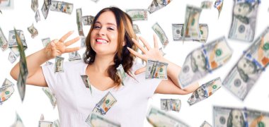 Beyaz günlük tişörtler giyen genç, güzel beyaz bir kadın 8 numaralı parmaklarıyla onu gösteriyor ve gülümsüyor. Kendinden emin ve mutlu..