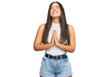 Genç, güzel İspanyol bir kız, günlük kıyafetler giyip, elleri bağlı yalvarıyor ve dua ediyor. Yüzünde umut ifadesi var. Çok duygusal ve endişeli. Yalvarıyor. 