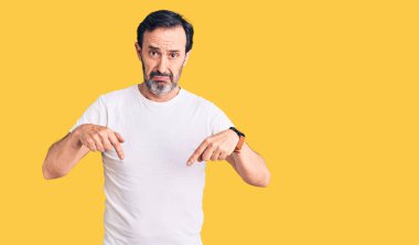 Orta yaşlı, yakışıklı, sıradan tişörtler giyen, üzgün ve üzgün görünen, yönünü parmaklarıyla gösteren mutsuz ve depresif bir adam.. 