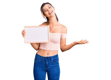 Genç, güzel bir kadın elinde boş beyaz bir karatahta ile zaferi kutluyor mutlu bir gülümsemeyle ve kazanan bir ifadeyle ellerini kaldırarak. 