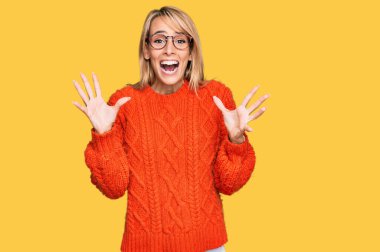 Güzel sarışın kadın, gündelik kıyafetler ve gözlük takıp çılgınlığı kutluyor ve başarıya hayret ediyor. Kolları açık, gözleri açık, heyecanla bağırıyor. Kazanan konsept 