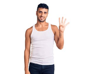 İspanyol asıllı genç adam, gündelik giysiler giyip dört numarayı gösterip işaret ederken kendinden emin ve mutlu bir şekilde gülümsüyor.. 