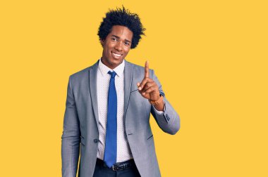 Afro saçlı, iş ceketi giyen yakışıklı Afro-Amerikan adam başarılı bir fikirle işaret ediyor. Heyecanlı ve mutlu. Bir numara.. 