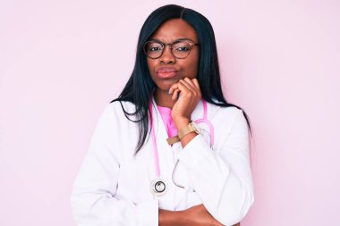 Doktor steteskobu takan genç Afrikalı Amerikalı kadın kollarını kavuşturup depresyondan sıkılmış ve yorgun göründüğünü düşünüyor.. 