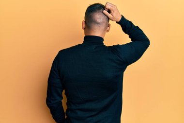 Balıkçı yaka kazak ve gözlük takan yakışıklı adam, elleri kafasında şüpheyi geriye doğru düşünüyor. 