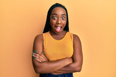 Kollarını kavuşturmuş genç Afro-Amerikalı kadın çılgın ve şaşkınlık dolu bir şekilde başarıyı kutluyor ve heyecanla haykırıyor.. 