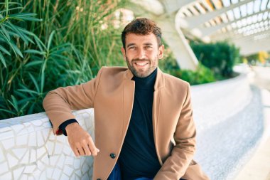 Zarif ceket giyen yakışıklı iş adamı dışarıda mutlu bir şekilde gülümsüyor.