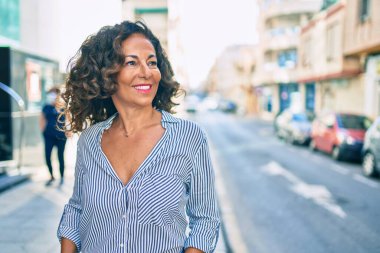 Orta yaşlı İspanyol kadın gülümseyerek şehirde mutlu mesut yürüyor..