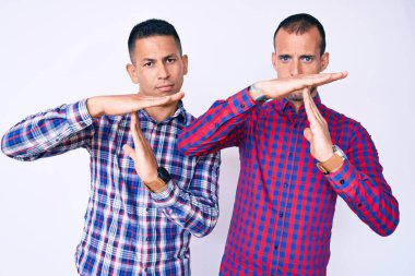 Gündelik giysiler giyen iki genç eşcinsel elleri ve ciddi yüzleri ile jest yapıyor. 