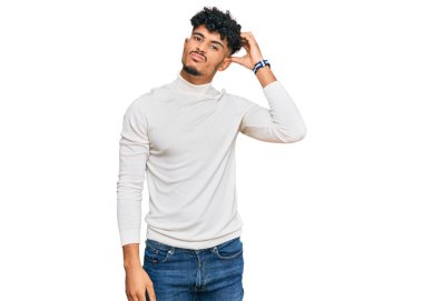 Kış süveteri giyen genç Arap adam soru sormayı ve kafasını karıştırıyor. Şüpheyle kararsız, kafa kafaya düşünerek. Düşünceli kavram. 