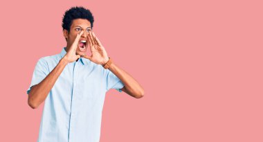 Gündelik kıyafetler giyen genç Afro-Amerikan adam elleri ağızda bağırarak bağırıyor. 