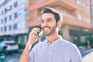 Genç İspanyol adam gülümsüyor. Şehirdeki akıllı telefondan konuşuyor..