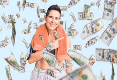 Kısa saçlı, spor kıyafetleri ve havlusu olan genç bir kadın. Akıllı telefon kullanıyor. Yüzünde mutlu ve doğal bir ifade olan el ve parmak ile yüzünü gösteren bir gülümseme var.