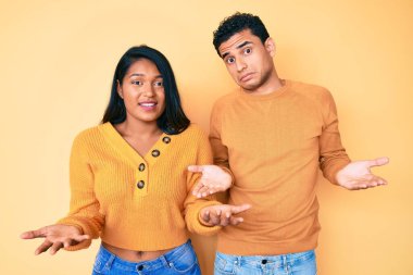 Güzel, Latin, genç bir çift, gündelik giysiler giyiyorlar. Hiçbir fikirleri yok ve kolları açık, hiçbir fikirleri yok.. 