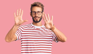 Sakallı, sıradan kıyafetler giyen, gözlüklü yakışıklı bir adam dokuz numarayı gösteriyor ve gülümsüyor. Kendinden emin ve mutlu.. 