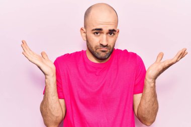 Gündelik tişört giyen genç, kel ve kafası karışık, kolları açık, hiçbir fikrim yok ve şüpheli bir yüzüm var.. 