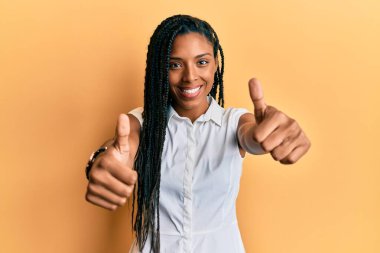 Afro-amerikan kadın gündelik giysiler giyip olumlu jestler yapıyor, gülümsüyor ve başarı için mutlu. kazanan jest. 