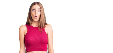 Zarif bir yaz tişörtü giyen genç, güzel sarışın kadın. Şaşırmış ve korkmuş bir ifade, korku ve heyecanlı bir yüz ifadesi var.. 