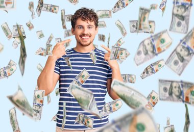 Kıvırcık saçlı, günlük kıyafetler giyen neşeli gülümseyen ve parmaklarıyla ve ağzıyla işaret eden genç, yakışıklı bir adam. diş sağlığı kavramı.