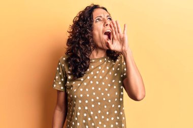 Orta yaşlı, güzel bir kadın, günlük tişört giyip el ele tutuşarak bağırıyor ve bağırıyor. iletişim konsepti. 