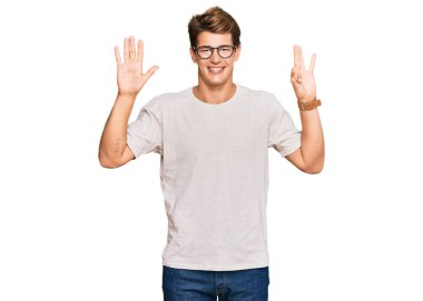 Yakışıklı beyaz adam, günlük kıyafetler ve gözlük takıyor. Sekiz numarayı gösteriyor ve işaret ediyor. Kendinden emin ve mutlu gülümsüyor.. 