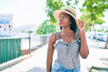 Genç Afro-Amerikan kadın tatilde gülümsüyor ve şehrin sokaklarında mutlu bir şekilde yürüyor.