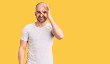 Genç, yakışıklı bir adam, sıradan bir tişört giyiyor. El hareketleriyle gülümsüyor, gözleriyle mutlu yüzüyle parmaklarının arasından bakıyor.. 