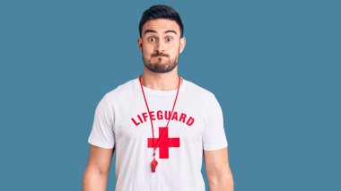 Cankurtaran üniforması giyen genç yakışıklı adam komik suratlı yanakları şişiriyor. Havayla şişmiş ağız, çılgın bir ifade.. 