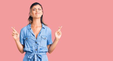 Genç ve güzel bir kadın, günlük kıyafetler giyip umut ve gözlerin kapalı gülümseyerek el sallıyor. Şans ve batıl inançlar. 