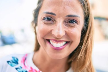 Genç İspanyol kadın gülümseyerek şehirde mutlu mesut duruyor.