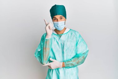 Cerrah üniforması giyen ve yüzünde kocaman bir gülümseme olan genç yakışıklı bir adam kameraya el ve parmak ile bakıyor.. 