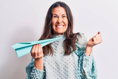 Genç, güzel esmer kadın, izole edilmiş beyaz arka plan üzerinde kağıt uçak tutuyor gururla bağırıyor, zaferi ve başarıyı kutluyor.