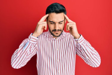 Kafası üstünde iş gömleği giyen genç bir İspanyol, stresten baş ağrısı çekiyor. migren ağrısı. 