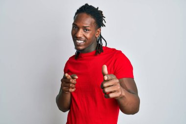 Sıradan giysiler giymiş, neşeli ve komik yüzüyle kamerayı işaret eden Afro-Amerikalı bir adam. iyi enerji ve titreşimler. 