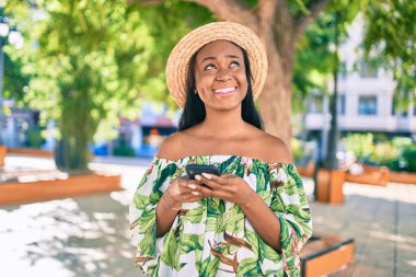 Genç Afro-Amerikan turist kadın tatilde gülümsüyor. Şehirde akıllı telefon kullanıyor..