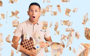 Satrancı elinde tutan yakışıklı Latin bir adam. Korkmuş ve ağzı açık kalmış, şaşırmış ve şaşırmış.